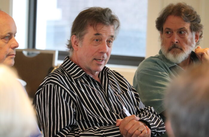 Three men in intense discussion during 2025 Super Summit